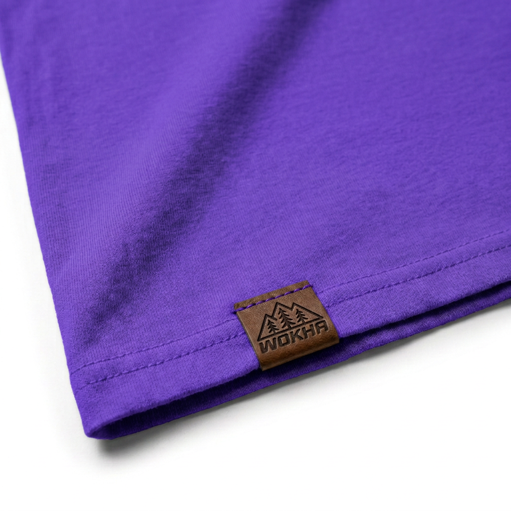 Detalle de la camiseta morada Wokha con etiqueta de cuero y logo grabado