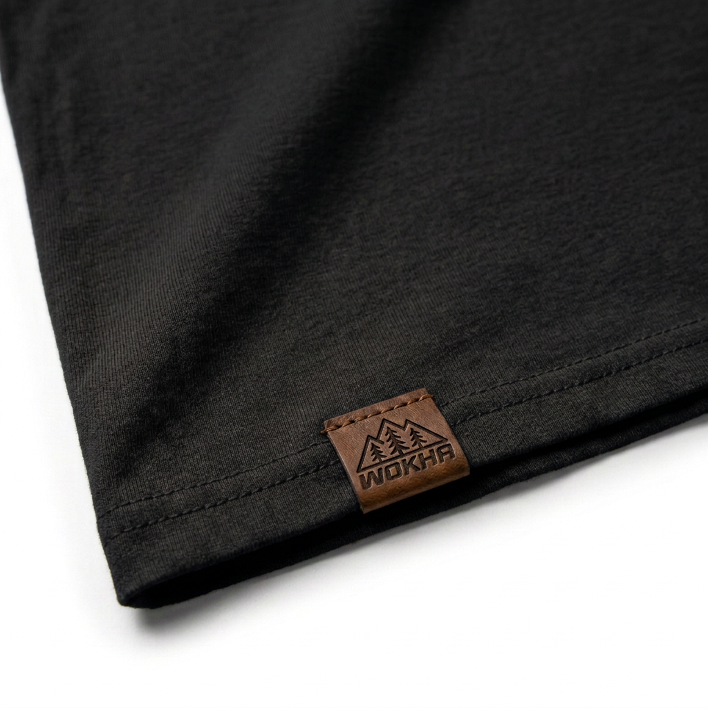 Detalle de la camiseta negra Wokha con etiqueta de cuero y logo grabado